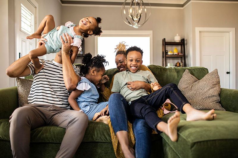 family of five playing on sofa at home