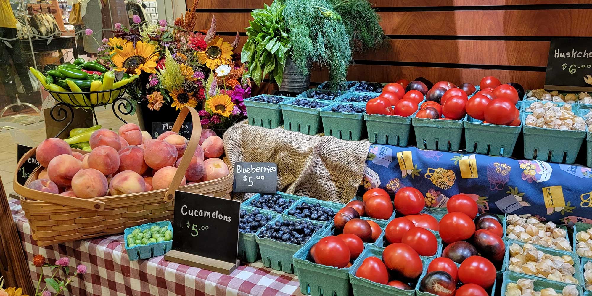 An assortment of fruits and vegetables available at a farm stand, including peaches, blueberries, tomatoes and garlic