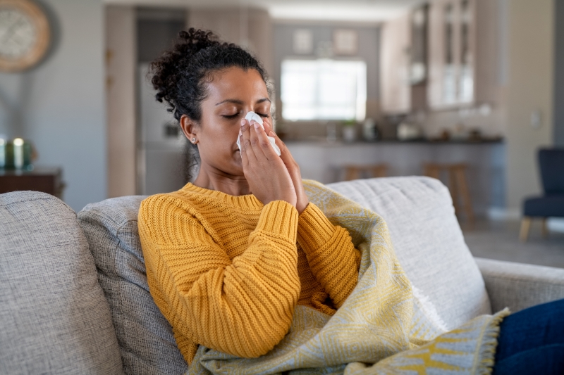woman on couch blowing her nose