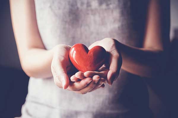 A woman holds a red heart in her hands