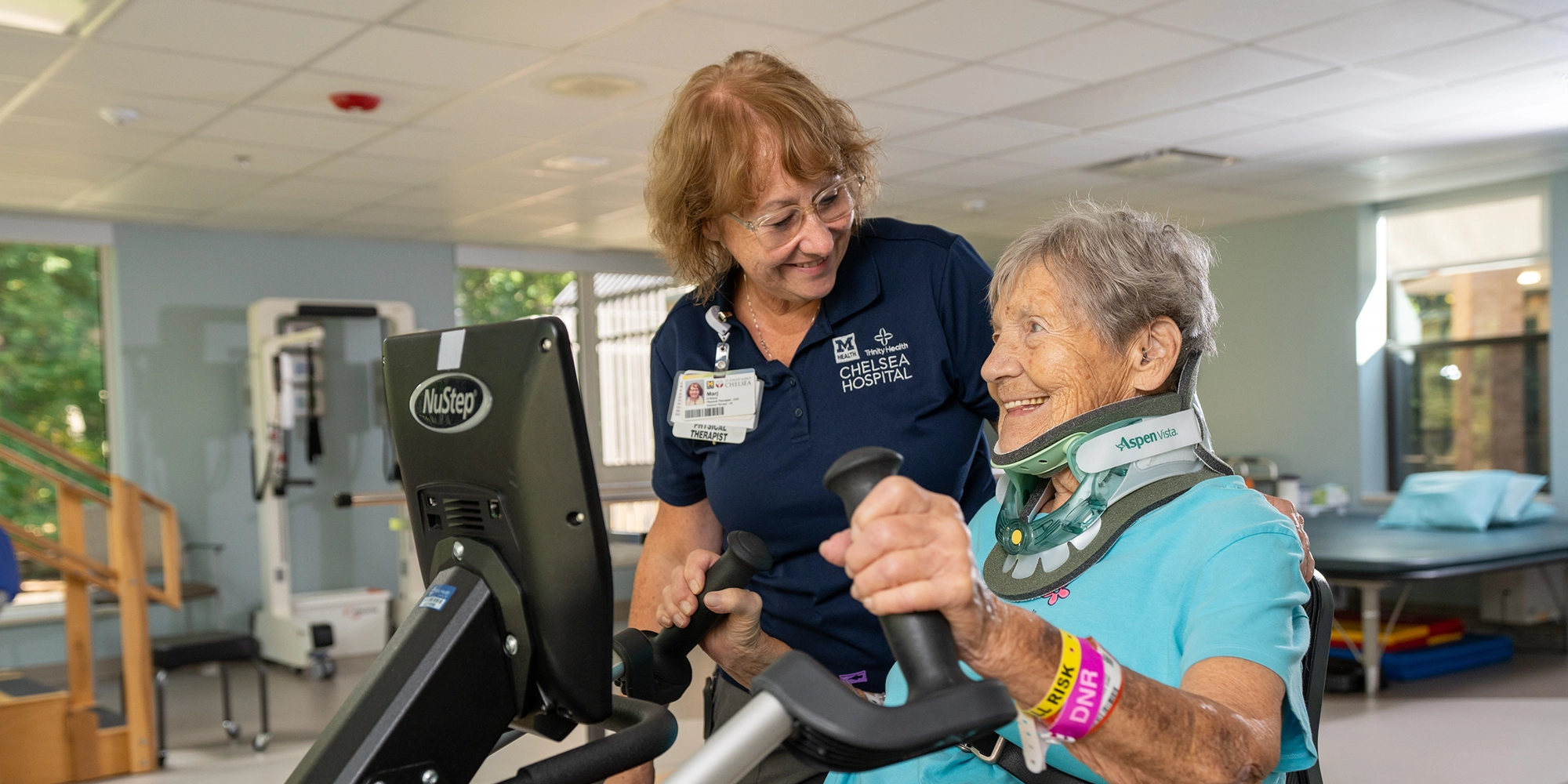 A female provider helps an elderly woman as she receives physical therapy at Chelsea Inpatient Rehab