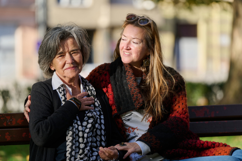 A mother and daughter smile together at a family gathering.