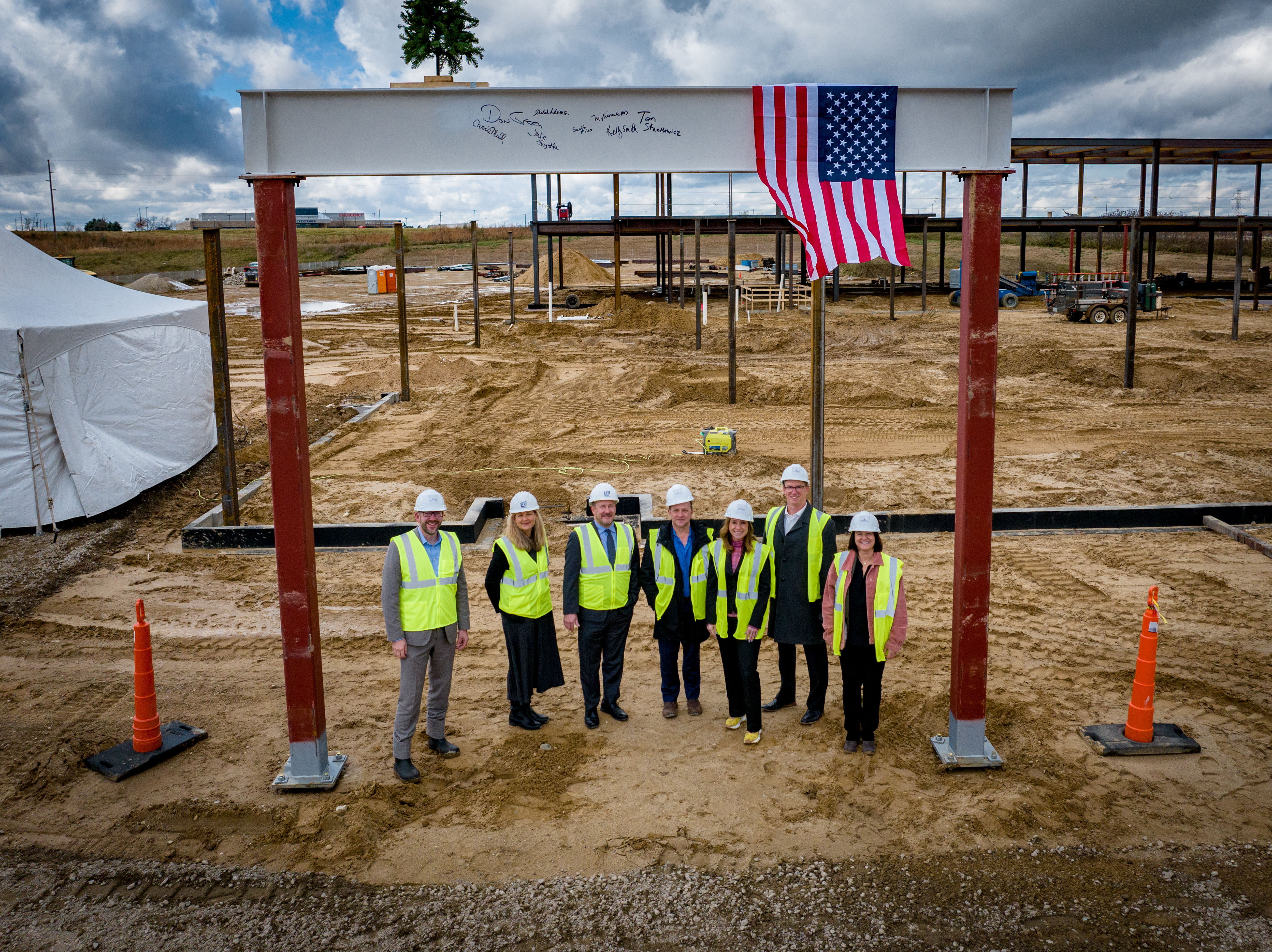 Trinity Health Michigan and UHS leaders stand under final beam during Beam Topping Ceremony