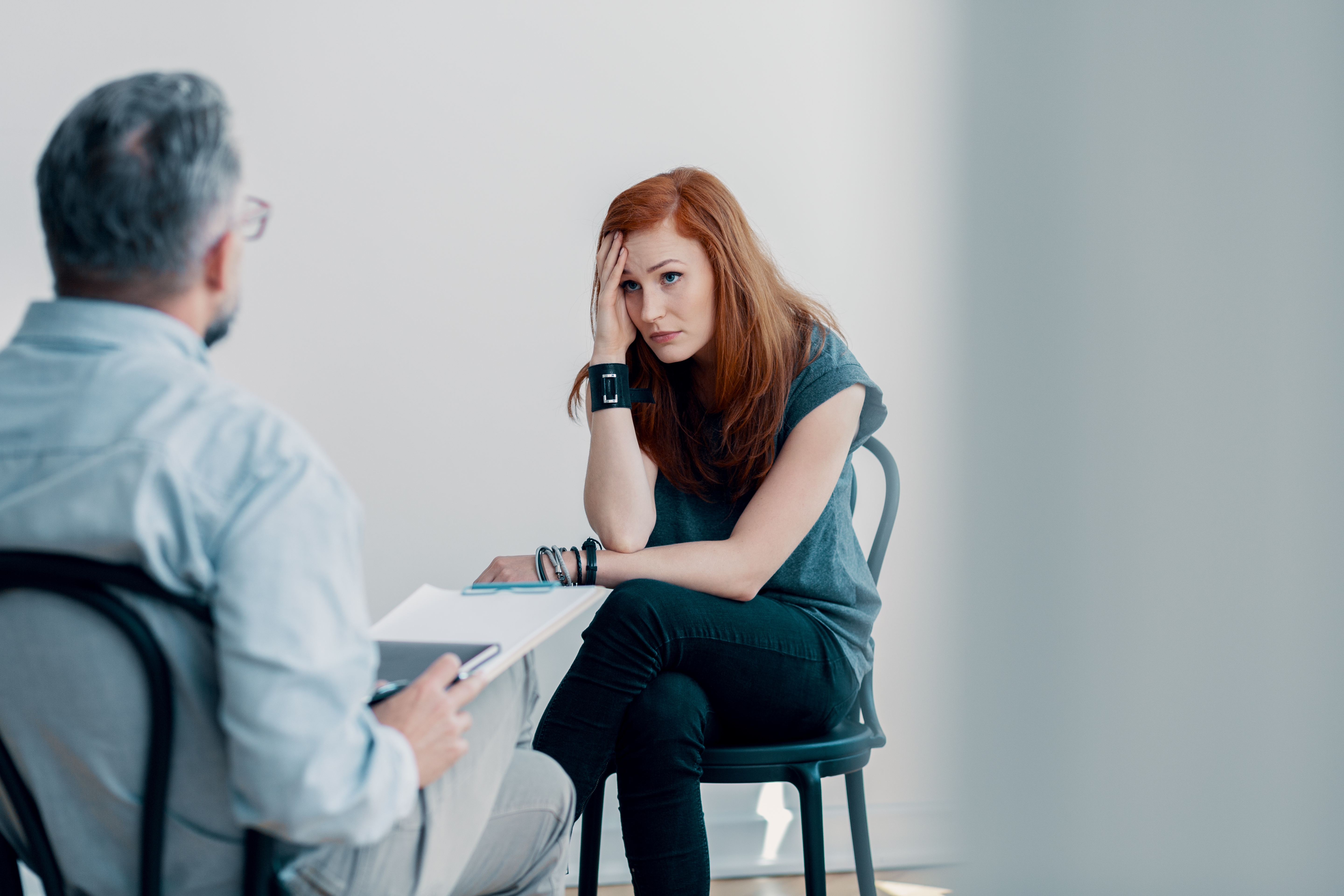 Scared Young Woman Talking To A Therapist About Abuse In A Bright Office