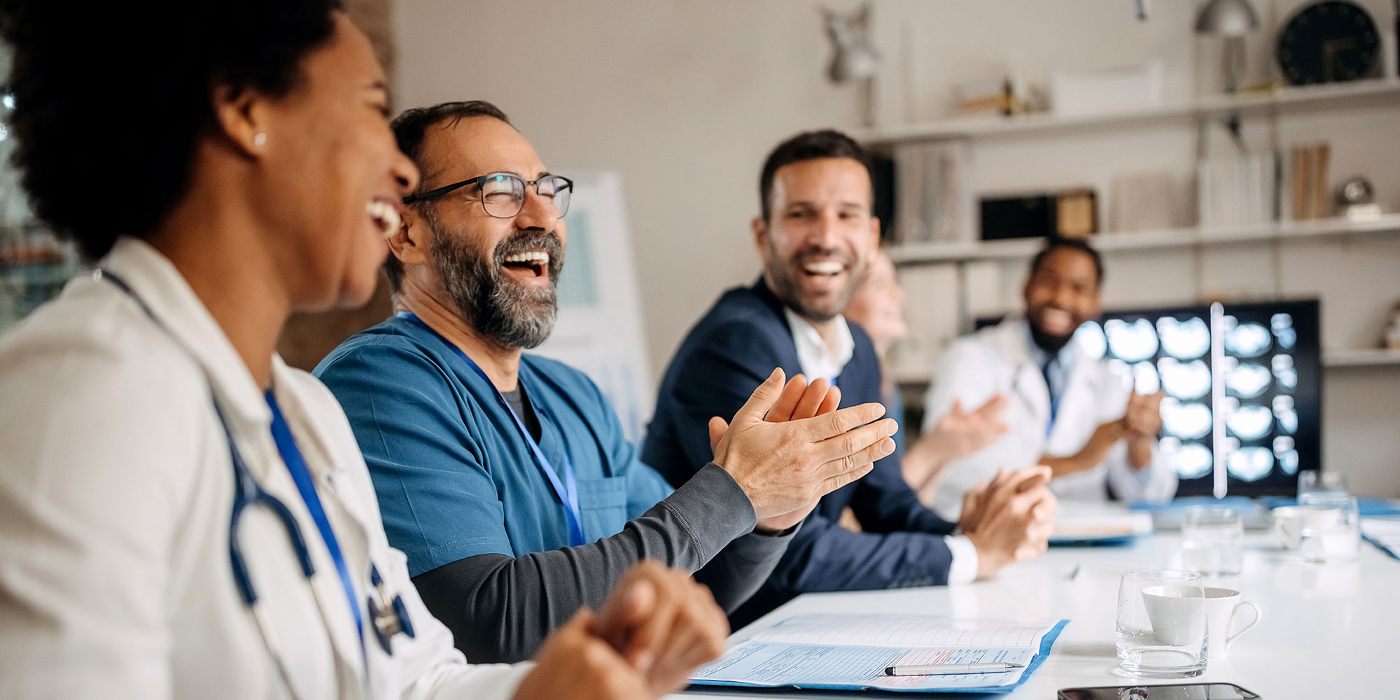 A group of healthcare workers share a laugh during a team meeting