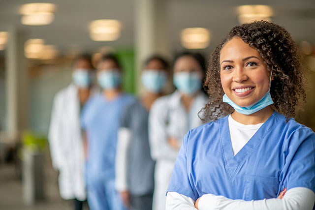 A group of expert breast care providers stand in a row and look at the camera